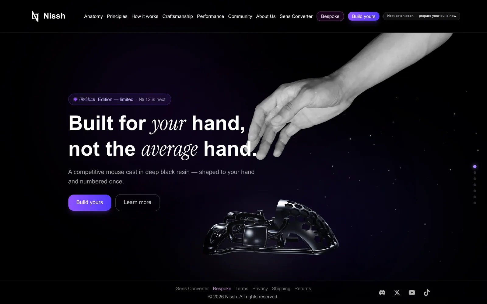 The nissh.gg home page: a greyscale hand reaching down from the top right, the headline Built for your hand, not the average hand, a line about a competitive mouse cast in deep black resin, shaped to your hand and numbered once, the Build yours and Learn more buttons, and the black lattice-shell mouse below.